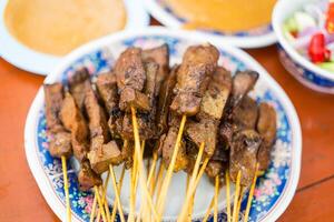 Liver satay or liver pork in bamboo skewers eaten with peanut sauce or sweet and sour sauce. photo