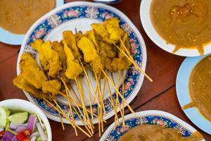 Pork satay marinated in milk on skewers eating with peanut sauce and pickles. photo
