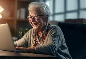 Radiant senior woman enjoys the warmth of her home, smiling while using a laptop, embracing the comfort of modern technology photo