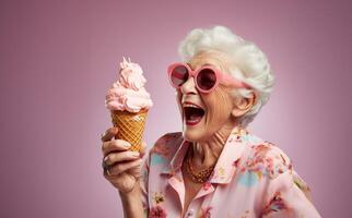 An elegant older woman, adorned with stylish sunglasses, enjoys a moment of indulgence as she savors ice cream, creating a vibrant and modern image against an isolated pink background photo