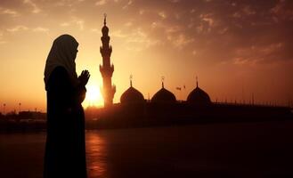 Silhouettes of a Muslim man and woman praying at a sacred site, bathed in the golden light of sunrise and sunset.Generated image photo
