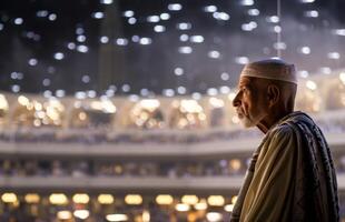 Elderly Muslim man in traditional attire standing in reverence before the Kaaba in Mecca..Generated image photo