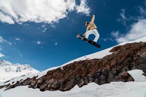 Professional snowboarder jumps high into the air from the kicker, taking the board with his hand while flying photo