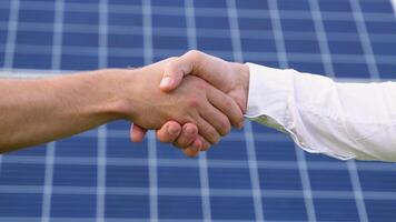 Two people having a shaking hands against solar panel after the conclusion of the agreement in the renewable energy video