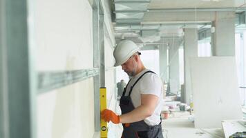 A man builder measures of the vertical deviation of plasterboard wall. Bubble level ruler video