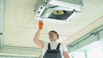 Worker installing or repairing ceiling air conditioning unit video