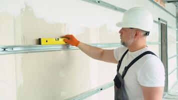 A man builder measures of the horizontal deviation of plasterboard wall video