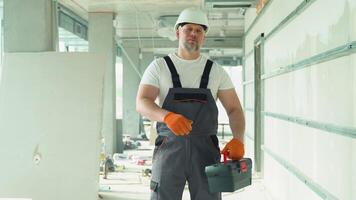 Positive 40s builder in safety helmet with tools on the construction site video