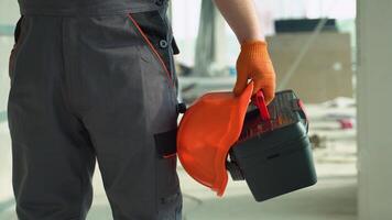Builder with tools and hardhat on the construction site, close up video