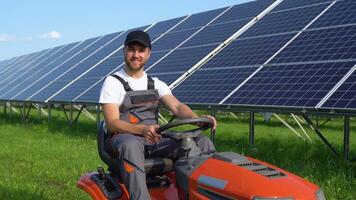 A man mows the grass near the solar panels. Green energy video
