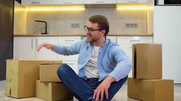 Young man moving in new home. Sitting on floor and relaxing after cleaning and unpacking video