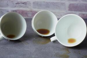 The table is cluttered with empty coffee cups, each still holding a few drops of leftover beverage photo
