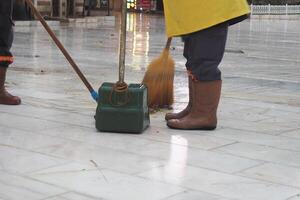 Workers are using a broom and dustpan to sweep the floor in a clean environment photo