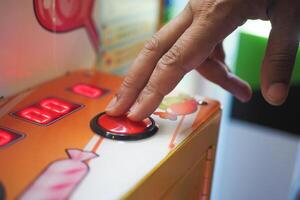 A CloseUp of a Hand Delicately Pressing a Colorful Button on a CandyThemed Arcade Machine photo