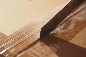 Utilizing a Cutting Tape on a Cardboard Box During the Process of Unpacking Items Carefully photo