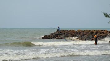 Fisherman standing at the seashore photo