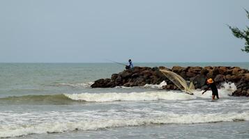 Fisherman standing at the seashore photo