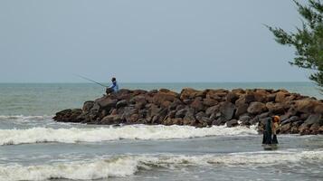 Fisherman standing at the seashore photo