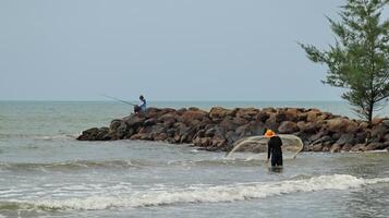 Fisherman standing at the seashore photo
