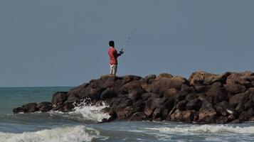 Fisherman standing at the seashore photo