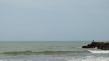 Fisherman standing at the seashore photo