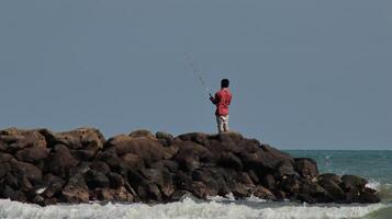 Fisherman standing at the seashore photo