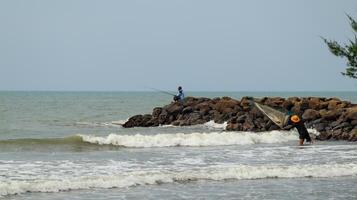 Fisherman standing at the seashore photo