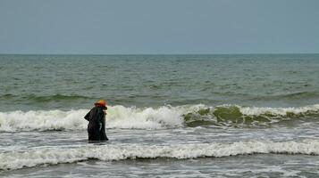 Fisherman standing at the seashore photo