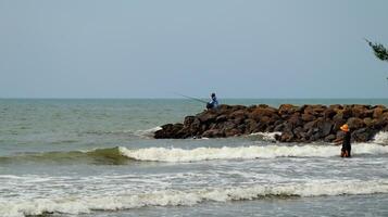 Fisherman standing at the seashore photo