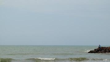 Fisherman standing at the seashore photo