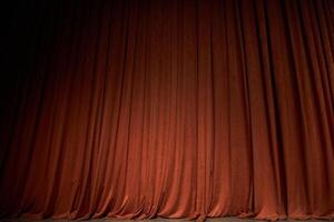 Orange closed curtain or drapes in theater with copy space. Theatrical performance concept. Spot of light on the curtain photo