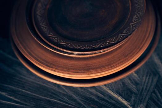 A stack of clay plates of different sizes on a dark background. Level position, top view. Ceramics plates are on a wooden shelf. photo