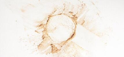 A neutral-colored face powder scattered on the surface in the form of a circle, on a light background banner. Top view, flat position. Mock up with gold powder with space to copy. photo