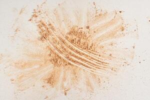 Face powder of neutral color, scattered on the surface on a light background. Top view, flat position. Gold powder layout with a space to copy. photo