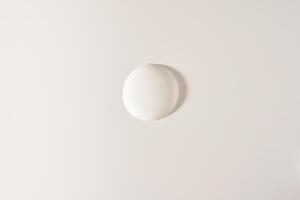 A round drop of cosmetic cream. A white creamy drop of skin care cream. A smooth drop isolated on a white background with space to copy photo