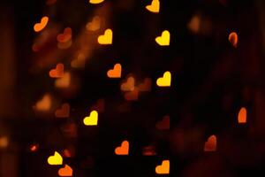 Abstract dark black confetti background for Valentine's Day. Overlay for your design with a space to copy. The hearts are defocused bright on a black background. photo