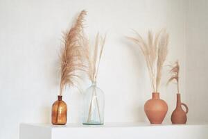 Podium in boho style. Product display with dried plants and flowers in amber glass, natural mock up with copy space. White wall and beige colours. photo