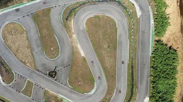 Drone rotating over go-karts racing on winding tracks from aerial view video