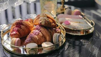 Croissants with glaze and macarons lie on the table. Breakfast of croissants and macarons video