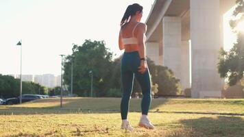 Sporty woman doing warm up exercises at city park during sunny day video