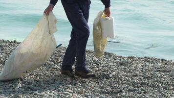 Man Cleaning up Beach with Garbage Bags and Container video