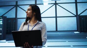 Admin in data center managing servers, operating systems and software programs. Tracking shot of woman in server hub ensuring networks are secure, up to date, and functioning properly, camera B video