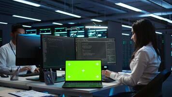 Programmers in data center manage and maintain databases using chroma key notebook, ensuring data integrity and security. Experts updating server room systems using isolated screen laptop, camera B video