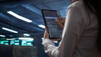 Data center software developer responsible for installation of networking equipment solving tasks on device. Close up of woman doing maintenance on server room infrastructure using tablet, camera B video