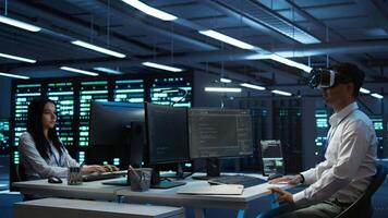 Admin in data center using virtual reality tech to ensure system can handle networking tasks. Server room worker wearing VR headset to track network traffic with PC, making improvements, camera B video