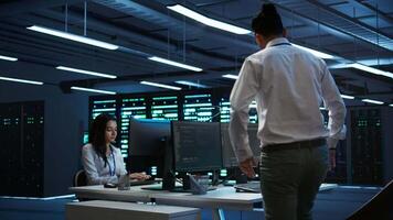 Engineer in data center installing software on computer, troubleshooting issues, handheld camera shot. IT professional in server hub establishing performance benchmarks, camera B video