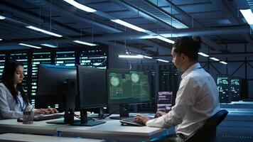 Team of technicians in server hub alerted by hacker passing firewall and stealing sensitive data. Coworkers panicking after seeing security breach notification on PC in data center workspace, camera B video