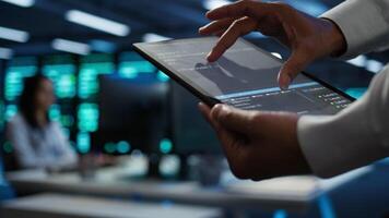 Programmer using device in data center, managing servers, operating systems. Close up of specialist in server hub using tablet to ensure networks are secure and functioning properly, camera B video