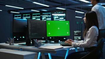 Technician using mockup computer in data center, managing servers, operating systems. Expert in server hub using green screen PC to ensure networks are secure and functioning properly, camera B video