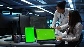 Engineer working with mockup laptop and tablet in data center used for managing gear energy consumption. Employee using green screen devices in workplace used for automation in server farm, camera B video